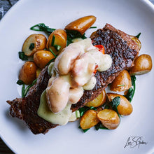 Cargar imagen en el visor de la galería, A plated Wagyu New York Steak with potatoes and a creamy sauce on top.